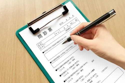今井歯科の清潔で明るい受付にて問診票を記入する初診診療の様子
